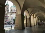 Mala Strana arched hallway with people and St Nicholas