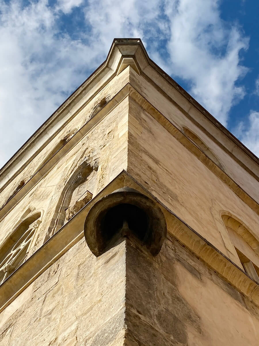 Looking up at the stone bell on building facade in Prague