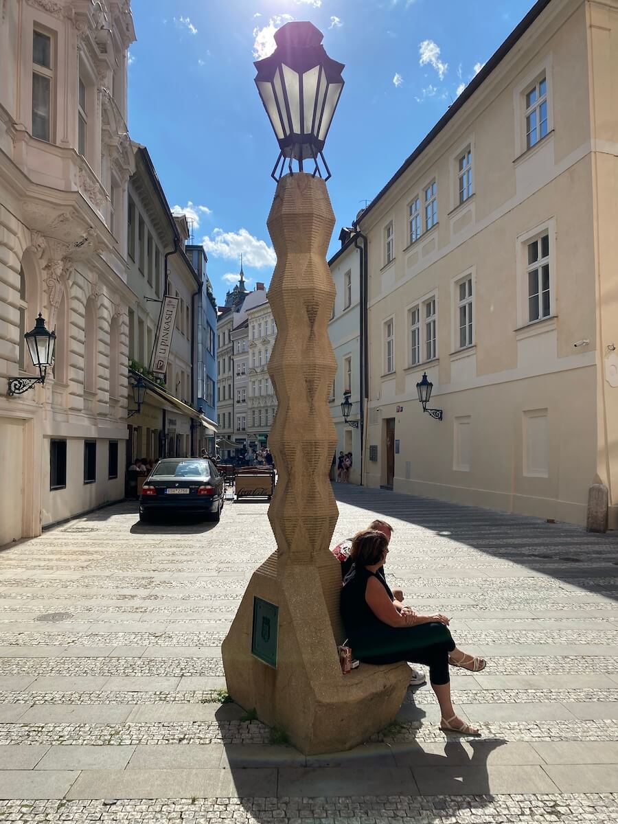 People sitting below Cubist lamppost in Prague