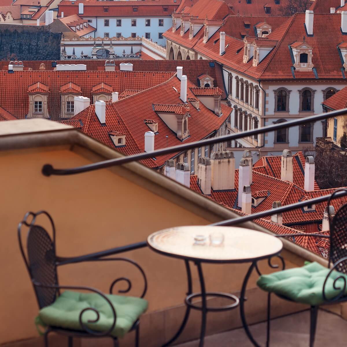 Chairs on balcony overlooking Prague rooftops