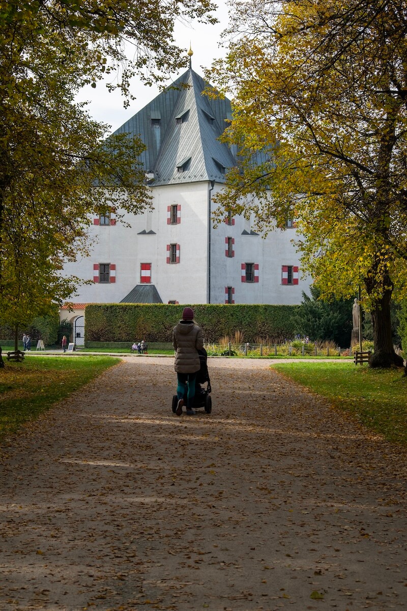 Vertical shot of mother pushing stroller with palace in distance